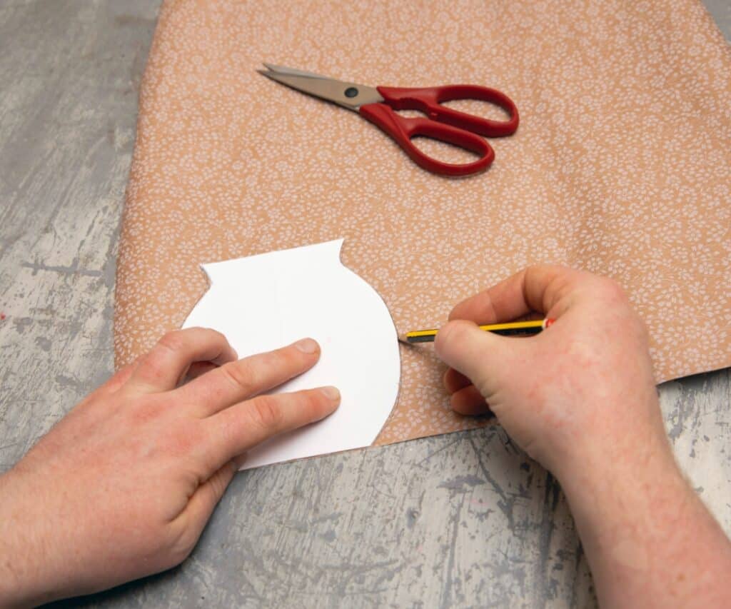 Hände zeichnen eine Form auf gemustertes Papier.