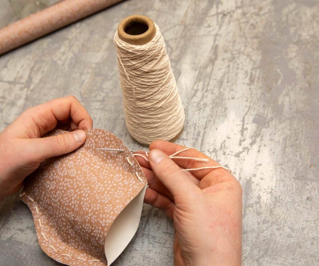 Papier wird mit einer Nadel und Faden zusammengenäht.