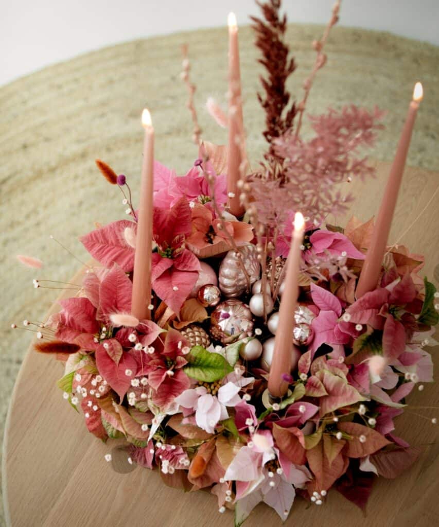 Boho-Adventskranz mit Weihnachtssternen in Rosa und Apricot, Trockenblumen, Gräsern und altrosa Stabkerzen.