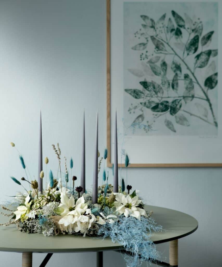 Moderne Tischdeko in kühlen Farben mit weißen Weihnachtssternen, Gräsern und Kerzen