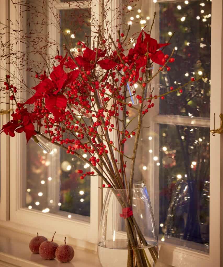Moderner Weihnachtsstrauß mit roten Weihnachtssternen in Reagenzgläsern, Ilexzweigen und Gräsern