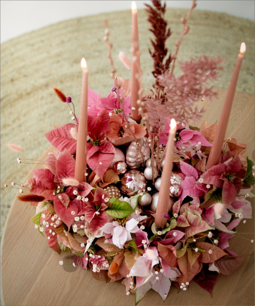 Adventskranz in Altrosa mit vielen geschnittenen Weihnachtssternen, Schleierkraut, Trockenblumen und Stabkerzen auf einem runden Beistelltisch aus Eichenholz