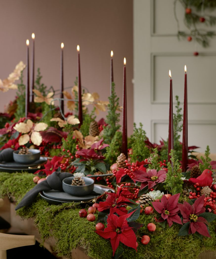 table filled with red poinsettia and candles