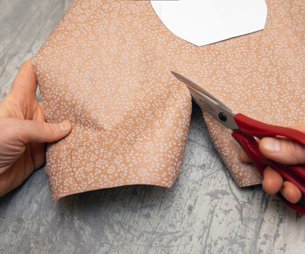 Des mains découpent la forme tracée dans le papier.