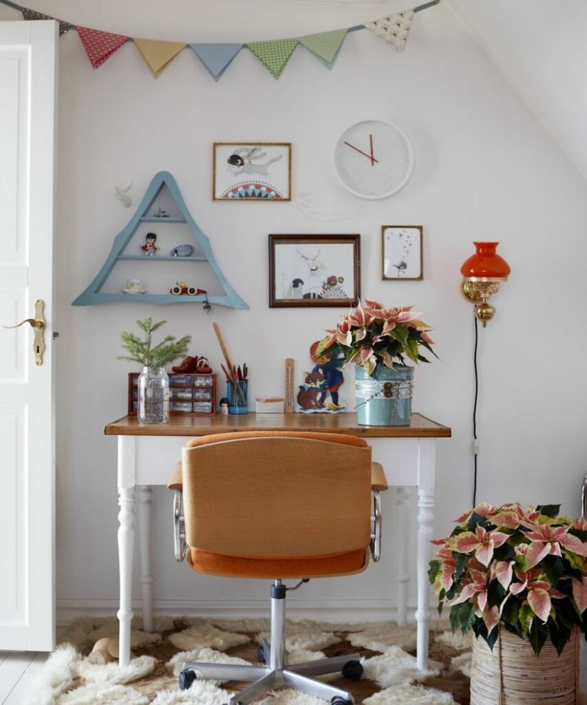 Egy világos, barátságos munkahely, ahol az íróasztalon egy kis mikulásvirág áll vödörben. A padlón több mikulásvirág cserépben díszíti a teret, ünnepi hangulatot kölcsönözve a helyiségnek.