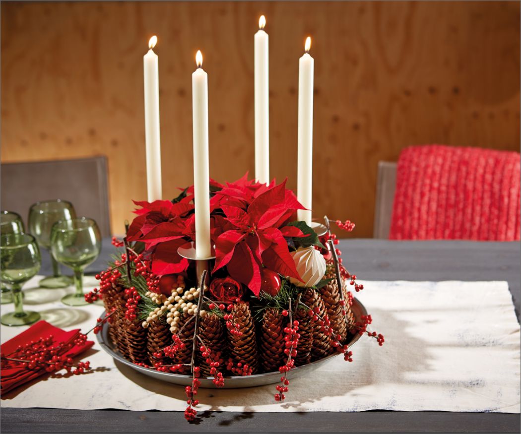 asset-6 Adventskranz im Landhausstil aus Zapfen, Weihnachtssternen, roten Beeren und weißen Kerzen auf einem grauen Tisch mit weißer Leinentischdecke